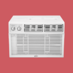 White window air conditioner with two control dials and front grille set against a red background