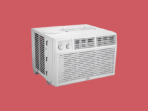 Portable window air conditioner unit with front vents and control dials on a red background ready for cooling a room