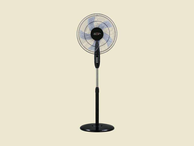 Black pedestal standing fan facing forward with visible blades and circular grill on a light beige background