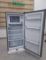 Open compact refrigerator in a showroom with a built in microwave on the upper left glass shelves and door racks are visible
