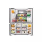 Open multi section refrigerator stocked with milk juice fruits vegetables and meats across shelves and drawers