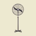 Black standing pedestal fan with a circular grille and four legged base on a pale yellow background