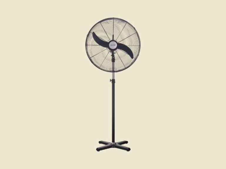 Black standing pedestal fan with a circular grille and four legged base on a pale yellow background