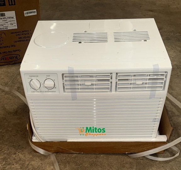 White portable air conditioner unit on a cardboard base on a concrete floor front has two horizontal vents a control panel with two knobs on the left and a colorful Mitos logo