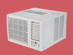 White window air conditioner with front grille and control panel against a red background