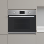 Built in stainless steel oven set in light gray kitchen cabinetry with a black glass door and control panel above the door