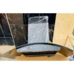 Curved car instrument cluster placed on a cardboard box with protective wrap and a cracked surface nearby