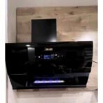 Black wall mounted kitchen range hood with a blue LED control panel and blue LED lights along the bottom mounted above the cooking area