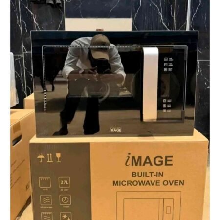 Built-in microwave oven on a cardboard box display; photographer's reflection appears in its glass door.