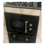 Built in black oven with brass door handle and control knobs in a wooden kitchen