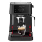 Front view of a black DeLonghi espresso machine with an adjustable drip tray a glass cup sits under the spout with red arrows indicating up down tray height adjustment