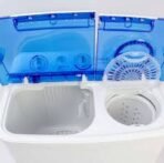 Top view of a compact twin tub washing machine with blue lids open to reveal two circular drums left for washing and right for spinning